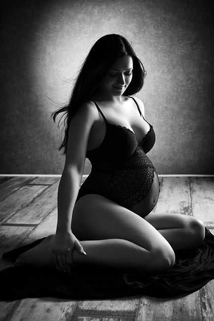 Babybauch Fotografie: Schwangere Frau sitzend mit schwarzem Schwangerschaftskleid